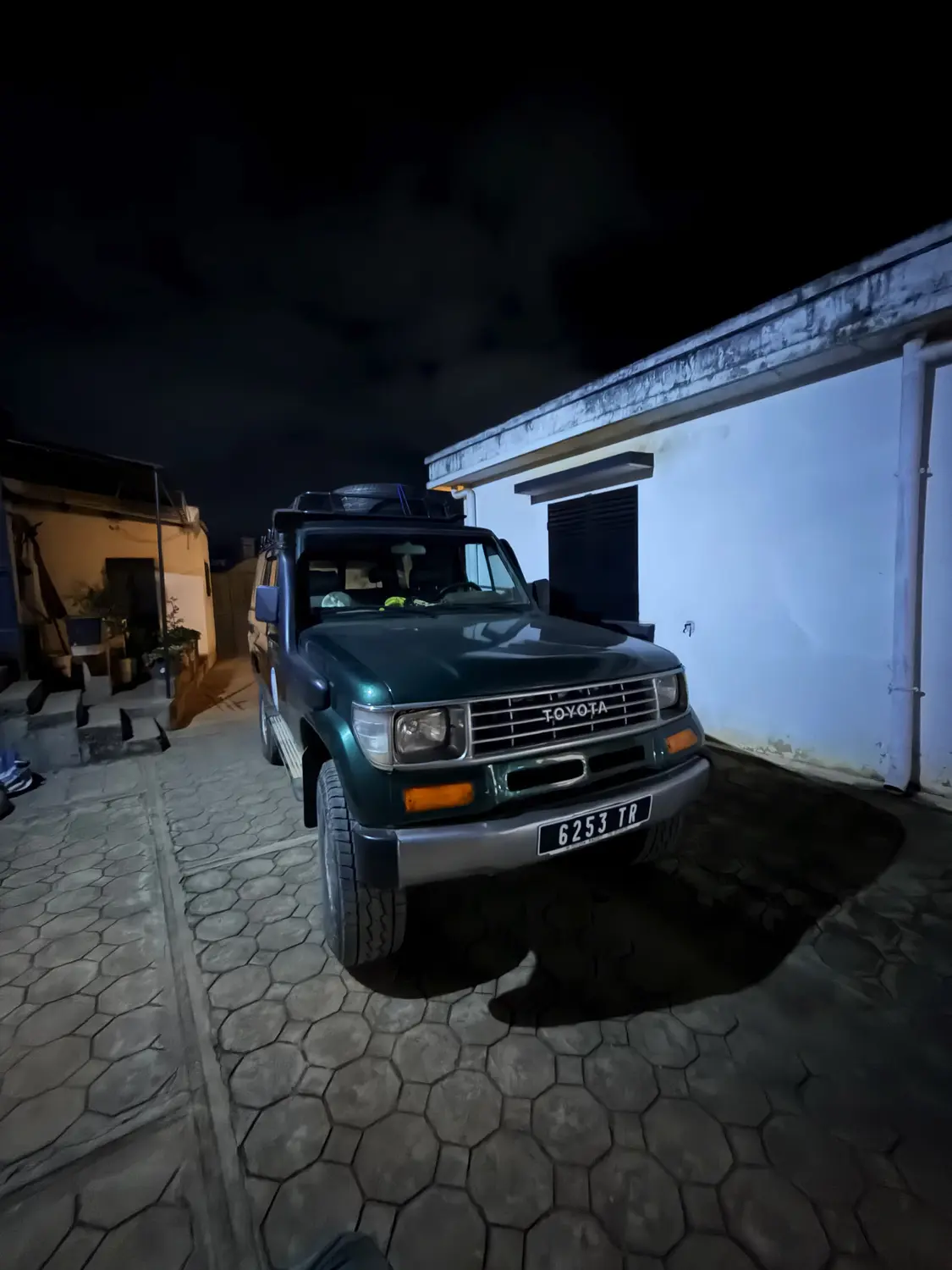 Our green Toyota 4x4 parked in a courtyard at night after a long day on the road