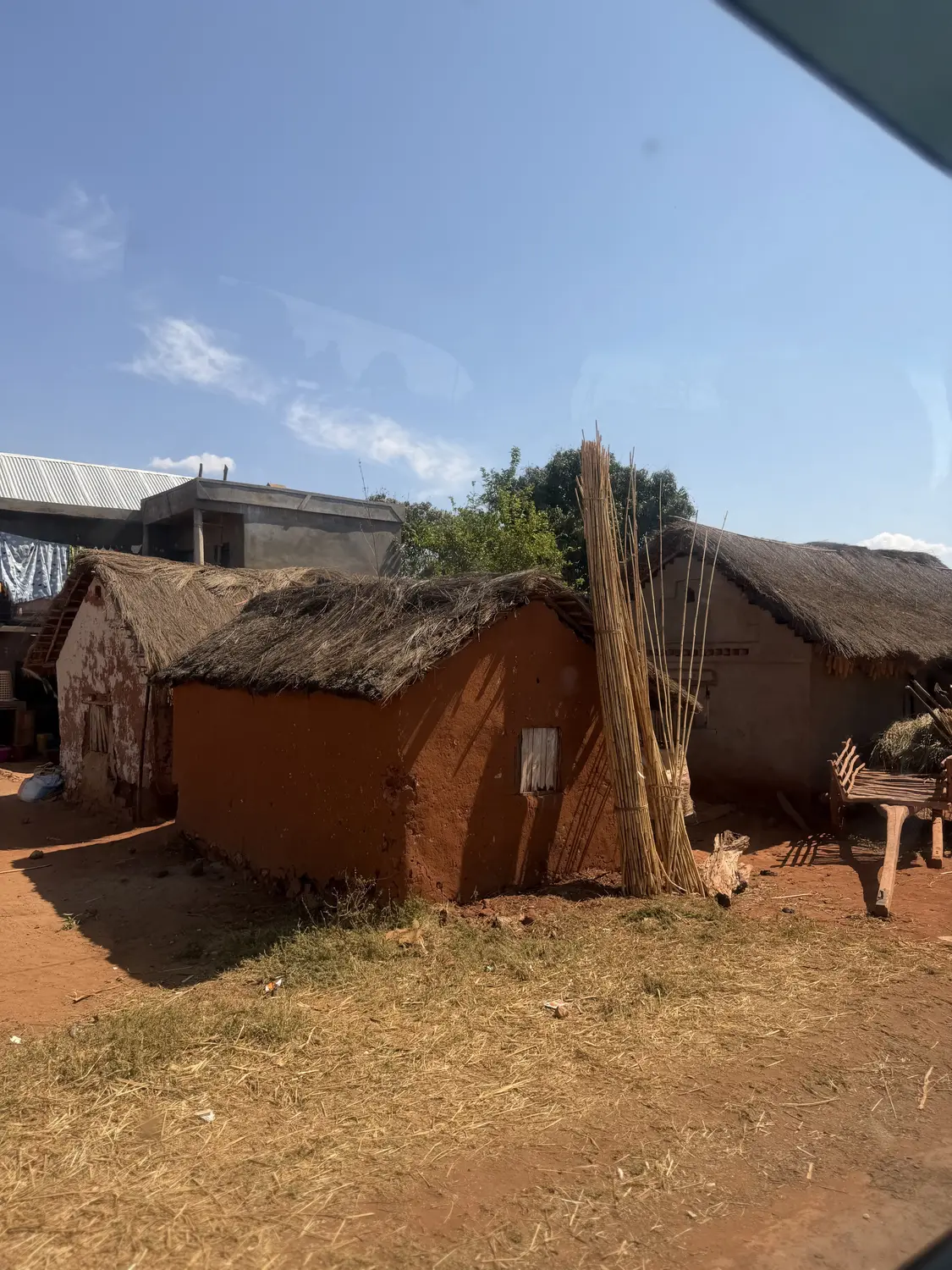 Red-earth houses with thatched roofs and bundles of reeds in a village along the highway