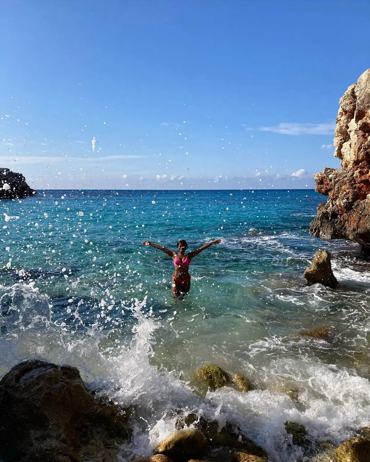 Melody splashing in the clear blue sea by the rocks in Mallorca