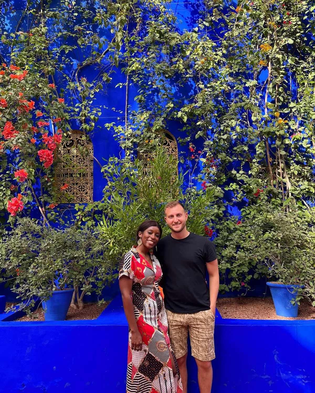 Us in front of the cobalt-blue wall and lush greenery of the Majorelle Garden
