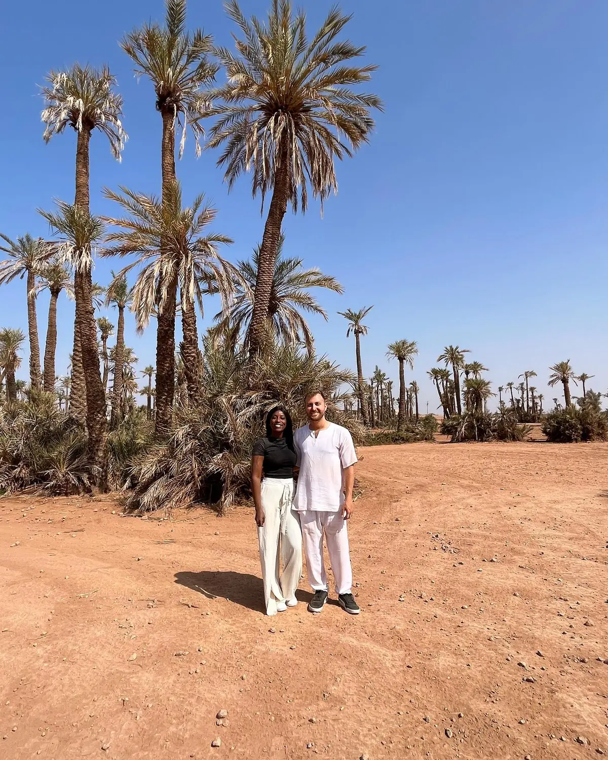 Us standing beneath tall date palms in the Marrakesh palm groves