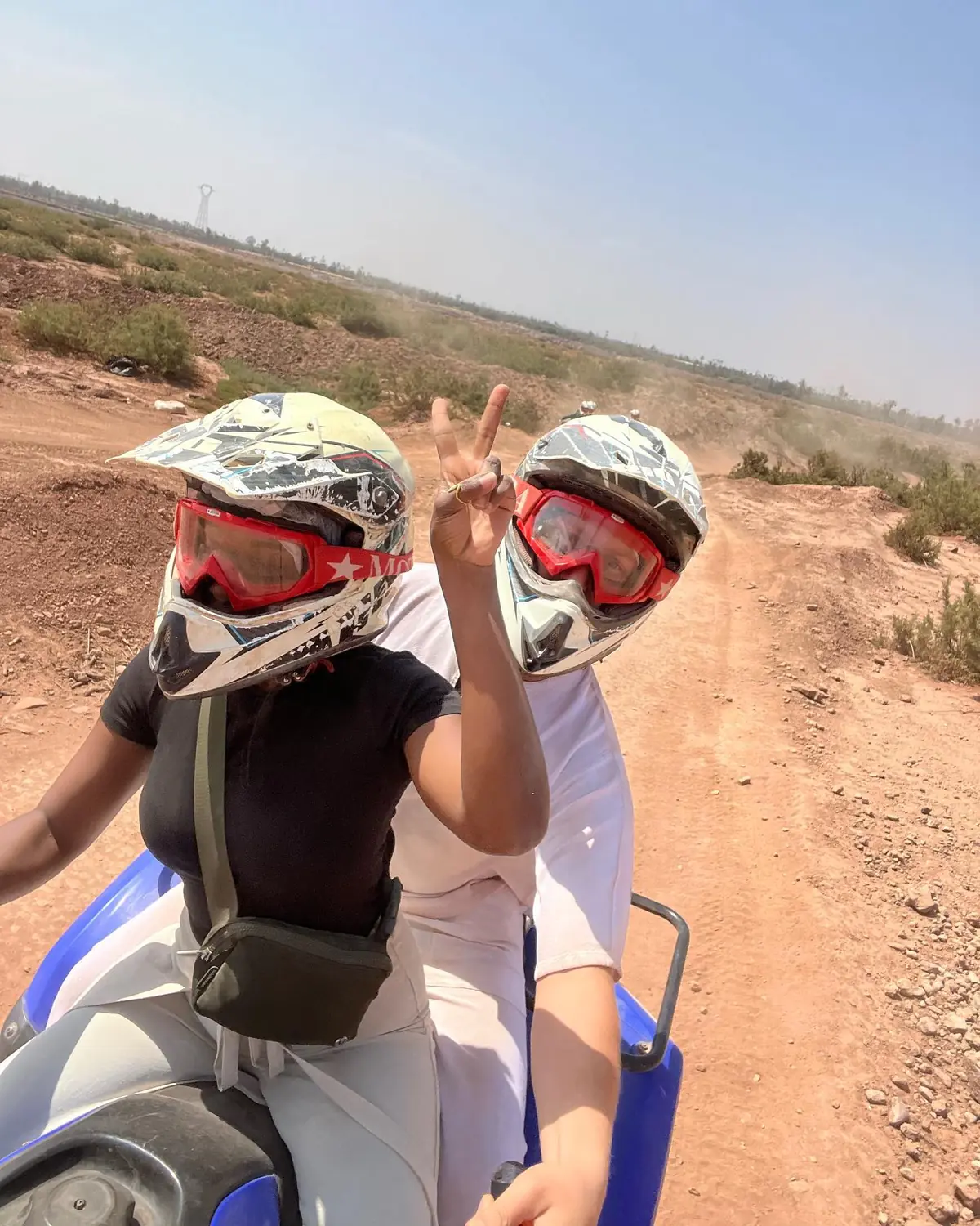 Helmet selfie on the quad bikes on a dusty desert track, Melody flashing a peace sign