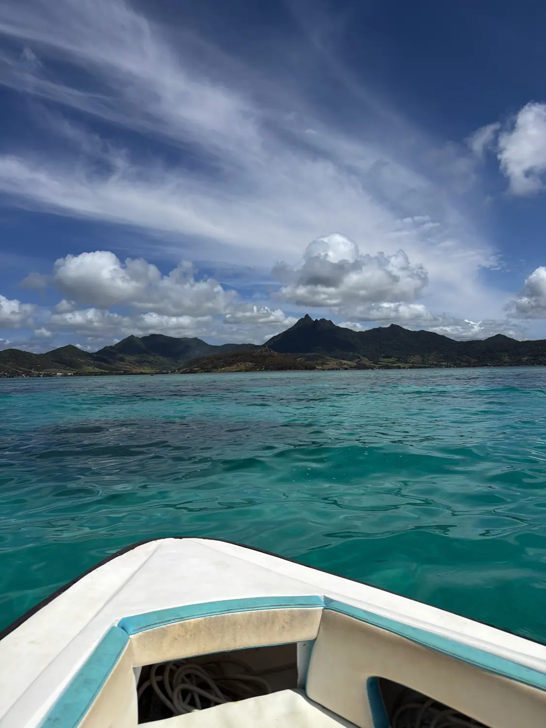 The bow of our speedboat in bright turquoise water with mountains ahead