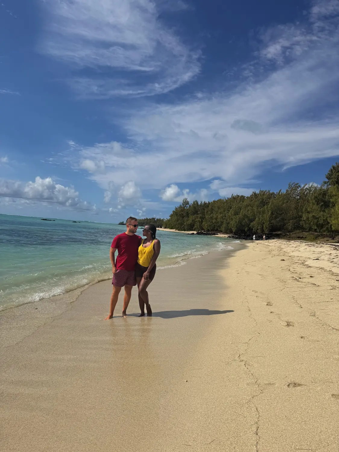 Us walking on the white sand of Île aux Cerfs next to turquoise water and casuarina trees