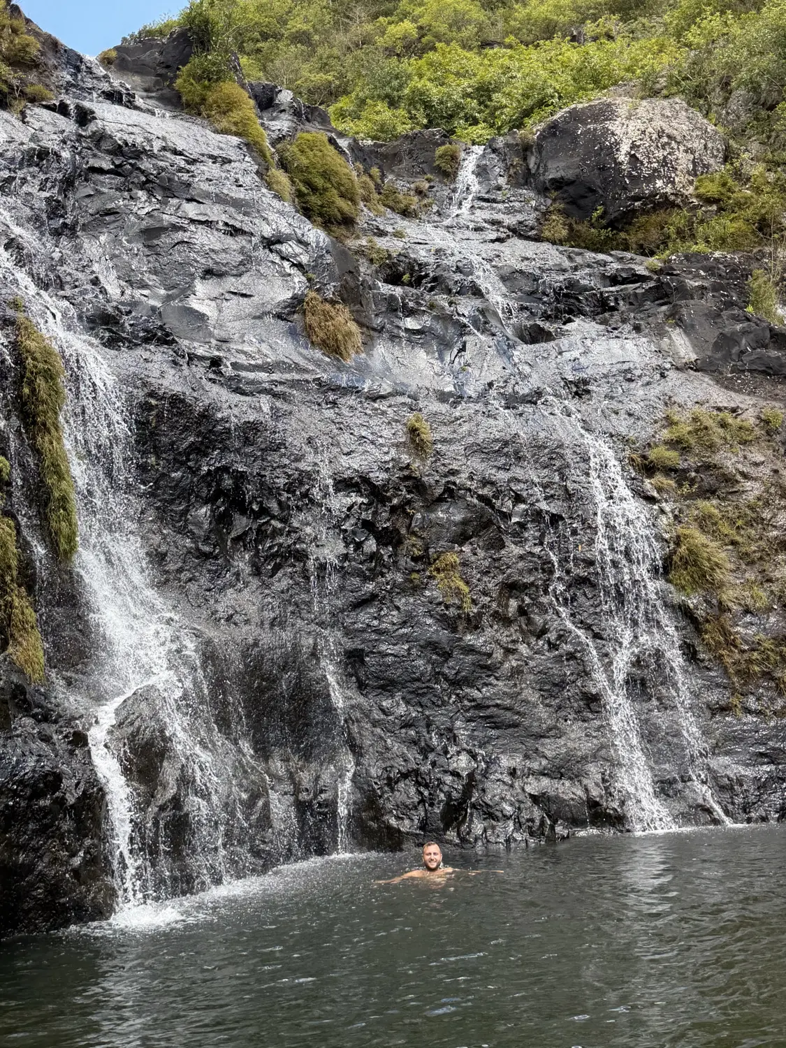 Andrew swimming in the natural pool at the base of a waterfall