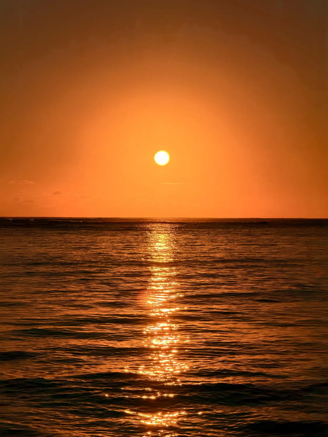 A bright sun low over a glowing orange sea
