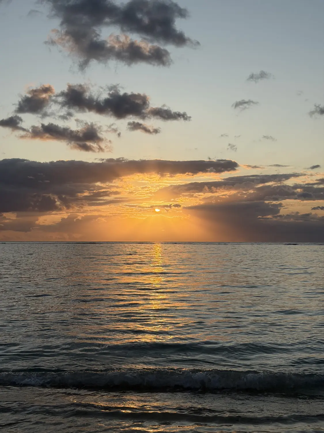 Sun rays bursting through clouds over the Indian Ocean at sunset