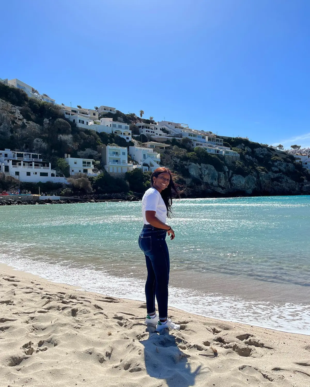 Melody on a sandy Menorca beach backed by white hillside houses
