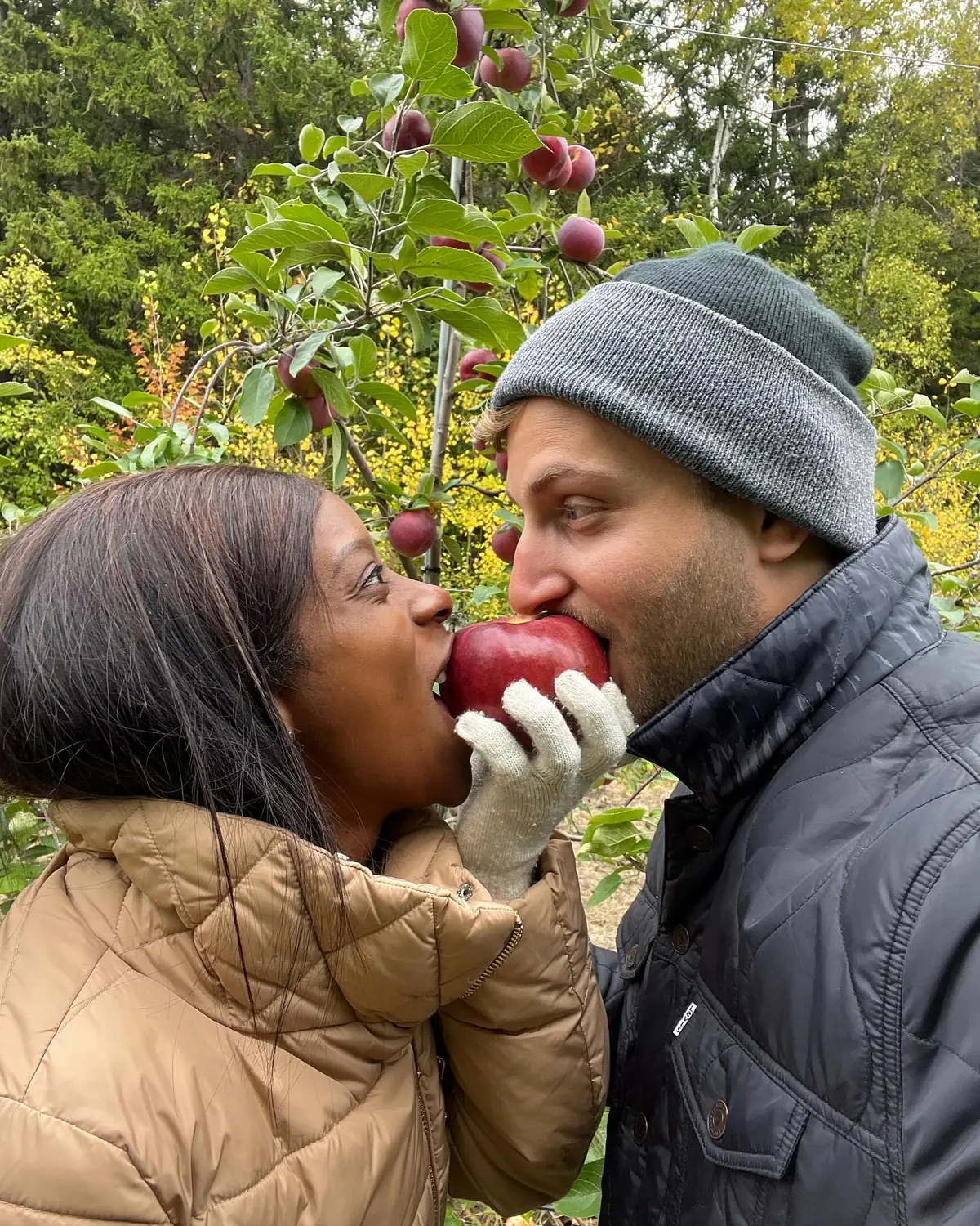 Us biting into the same red apple at a Montreal orchard in autumn