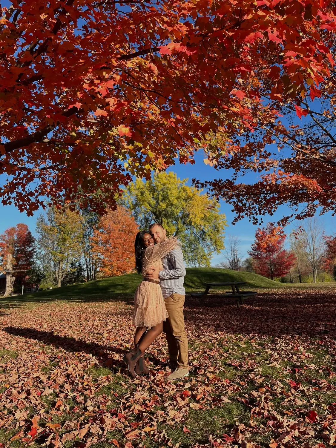 Us hugging under a brilliant red maple in a Montreal park in autumn