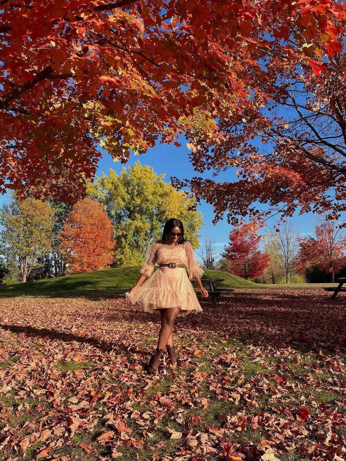 Melody twirling in a park under fiery red autumn maples in Montreal