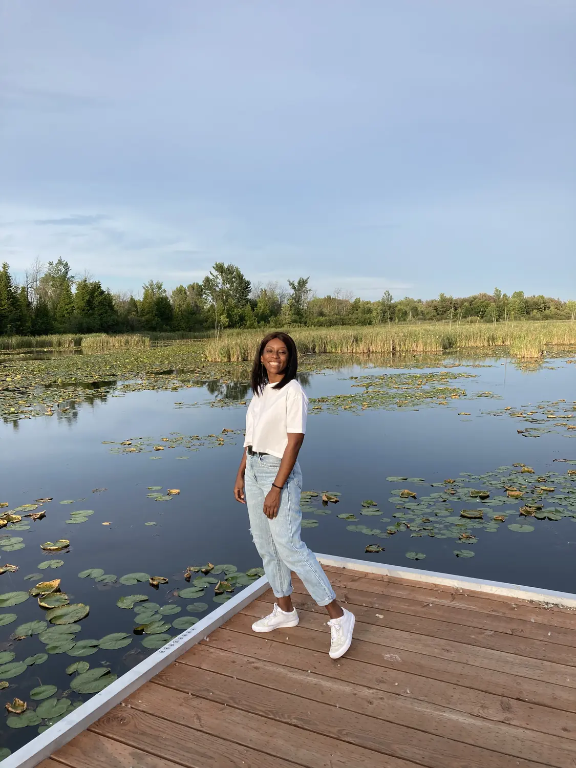 Melody on a wooden boardwalk over a lily-covered pond at Île-Bizard nature park