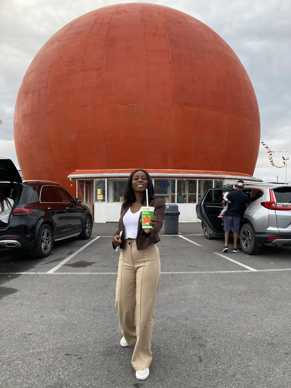Melody with a drink in front of the giant orange Gibeau Orange Julep in Montreal
