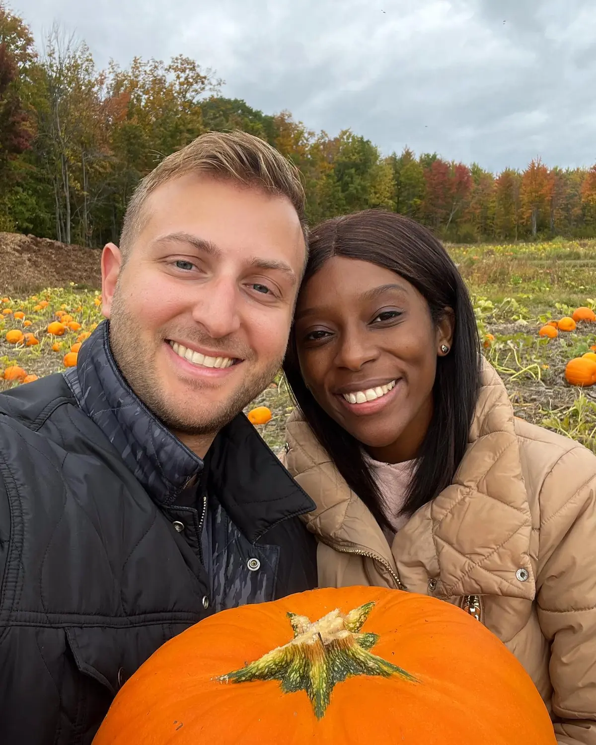 Selfie of us in a pumpkin patch holding a pumpkin near Montreal in autumn