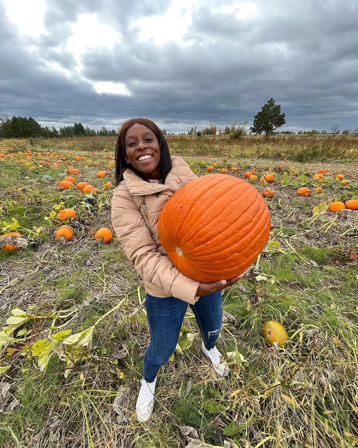 Melody holding up a large pumpkin in a pumpkin field near Montreal