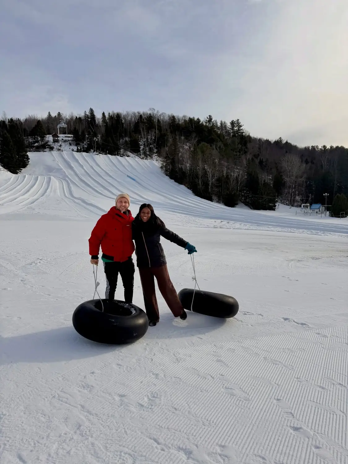 Us holding snow tubes at the bottom of a tubing hill in Saint-Sauveur