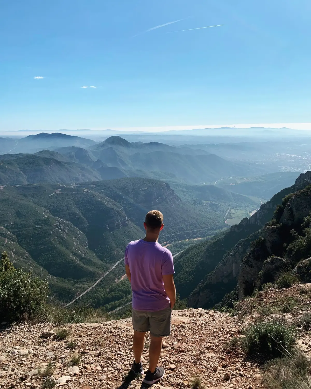 Andrew looking out over the green valley and distant plains from the top of Montserrat