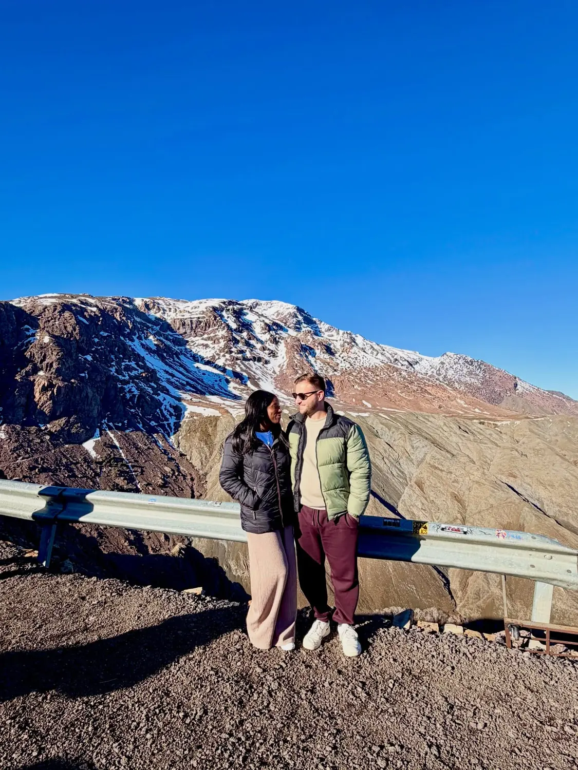 Us at a snow-dusted High Atlas mountain pass viewpoint
