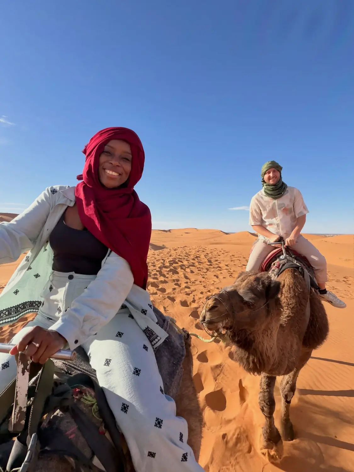 Us riding camels across the Sahara dunes, both in Berber headscarves