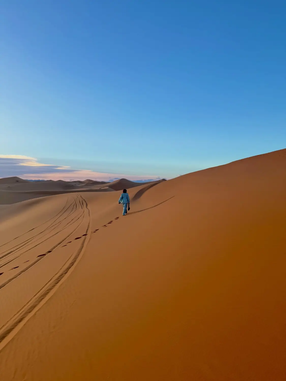 A lone figure walking the dunes at dusk