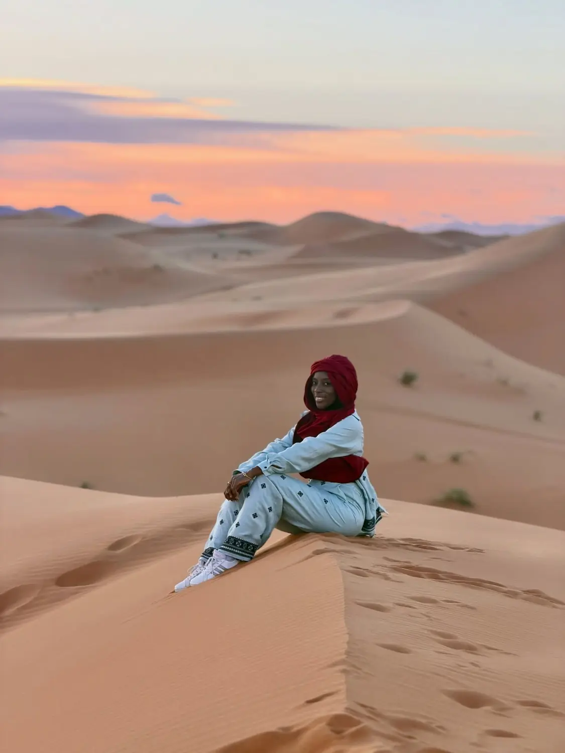 Melody on a dune at sunset in a red headscarf