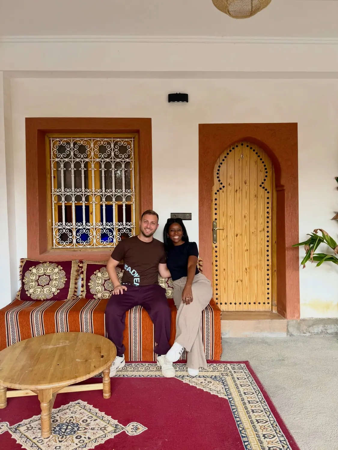 Us sitting on a Berber banquette outside a carved wooden riad door