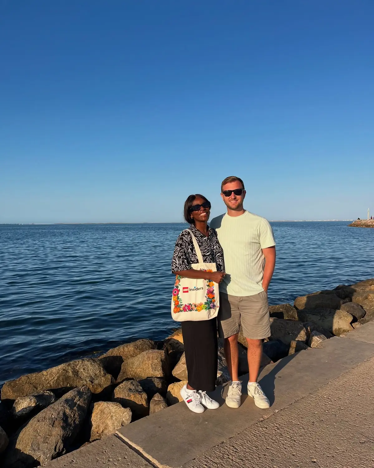 Us on the rocky breakwater beside the calm blue Mar Chica lagoon at Nador