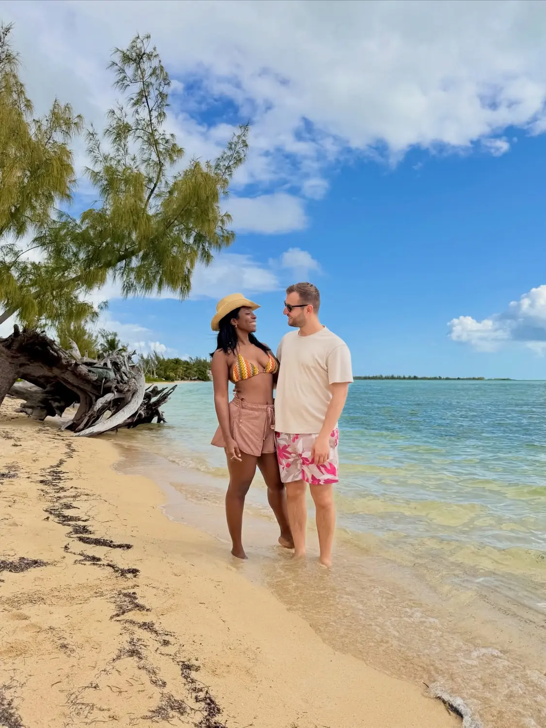 Us walking together along a palm-lined beach looking at each other