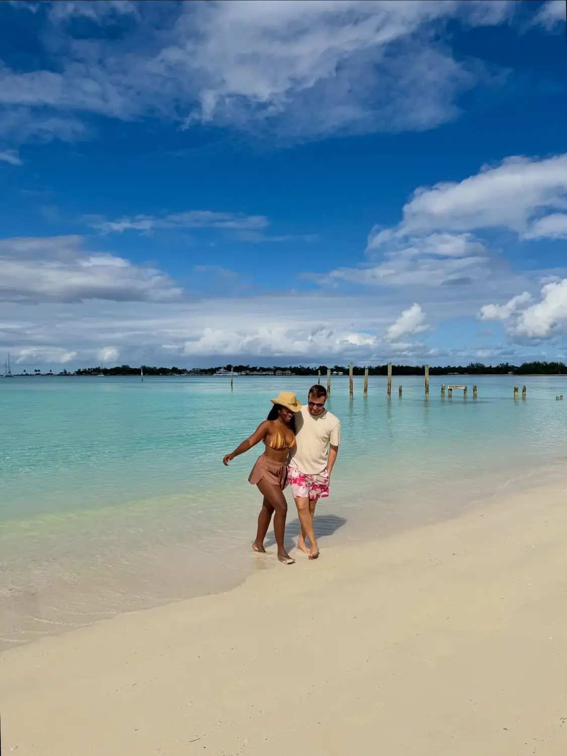 Walking a shallow sandbar past old weathered pier pilings