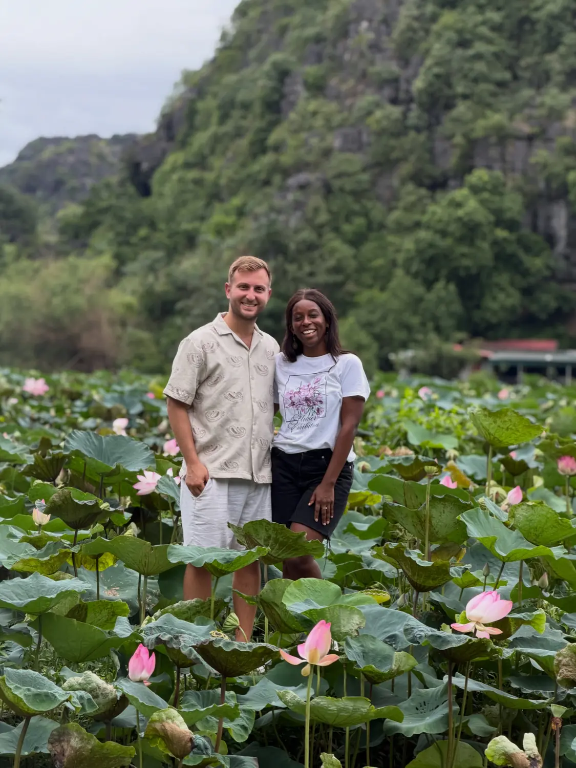 Us standing among tall pink lotus flowers below the karst mountains