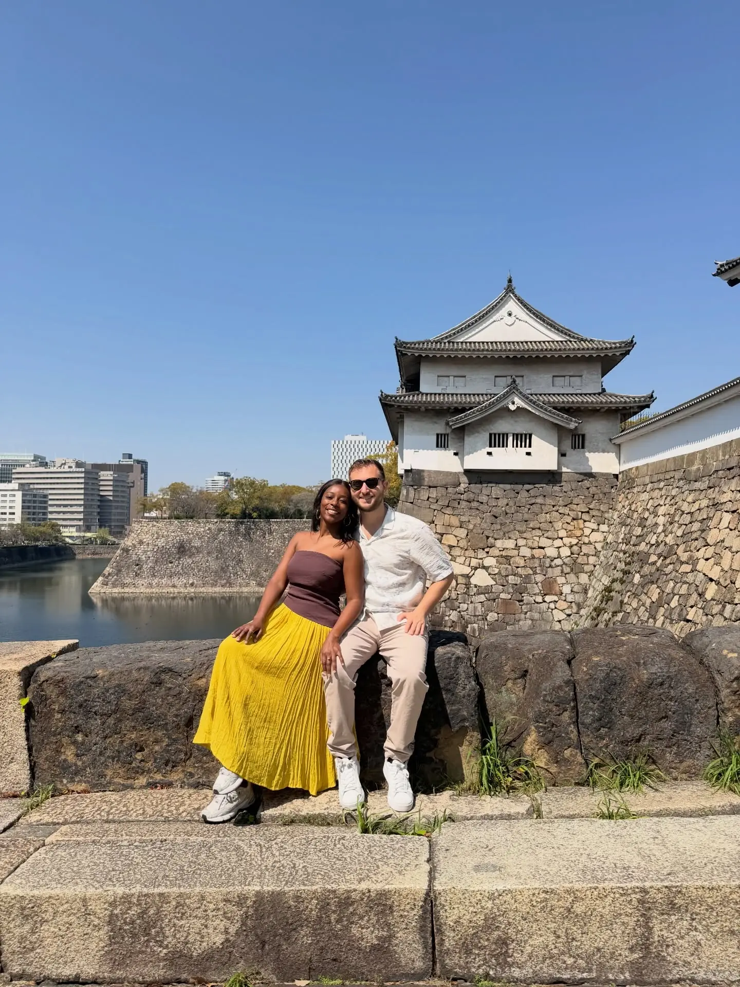 Us sitting on the wall by an Osaka Castle turret and moat