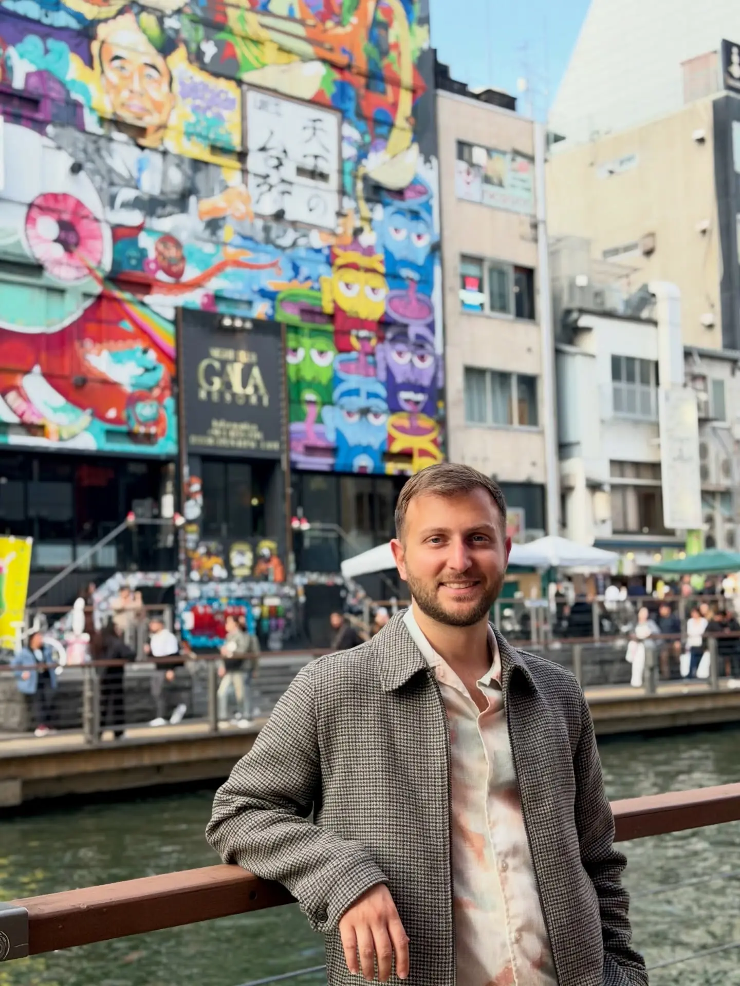 On the canal bridge in front of Dotonbori's colourful murals