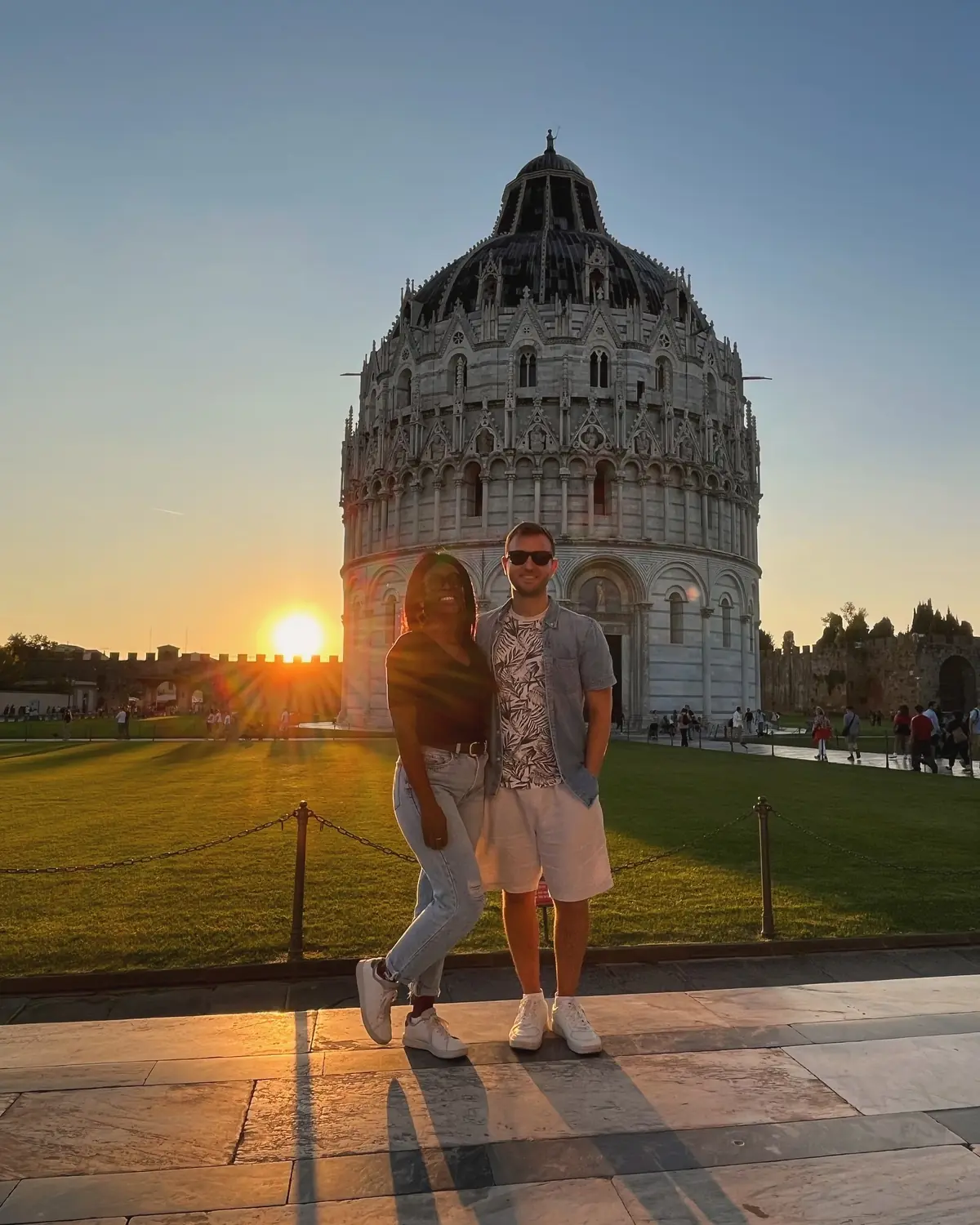 Us in front of the round Pisa Baptistery with the sun setting behind