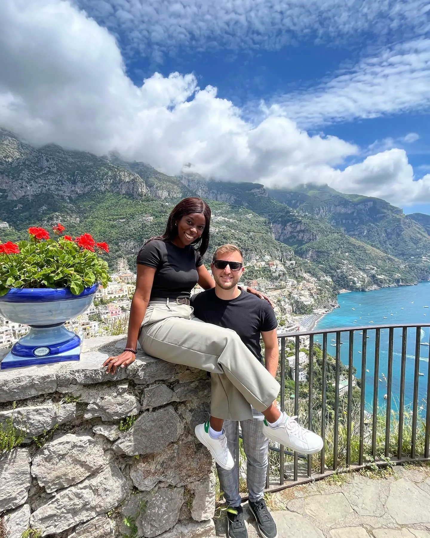 Resting on a stone wall by a blue ceramic urn over Positano