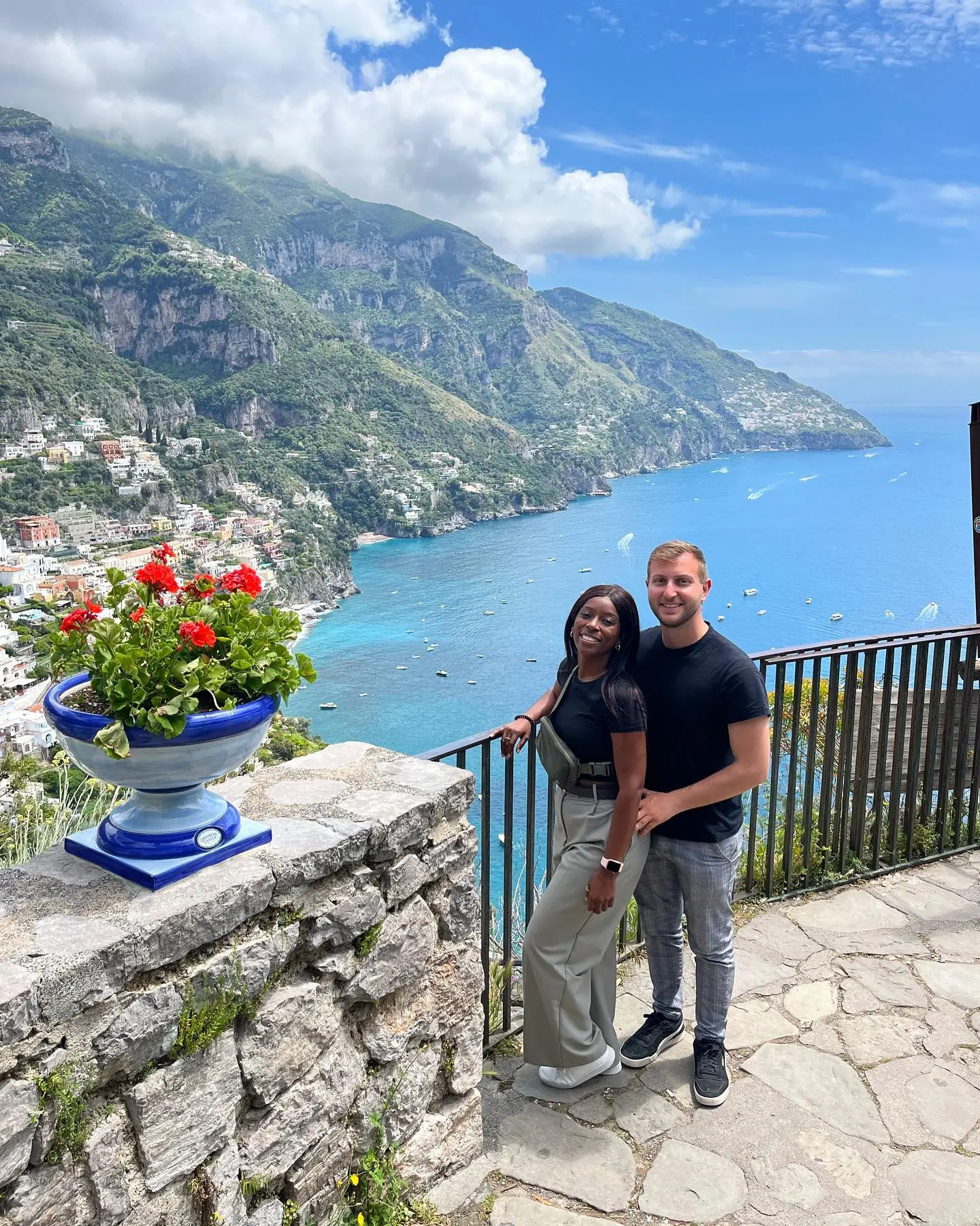 Standing above the bay by a blue urn of red geraniums, boats dotting the sea below