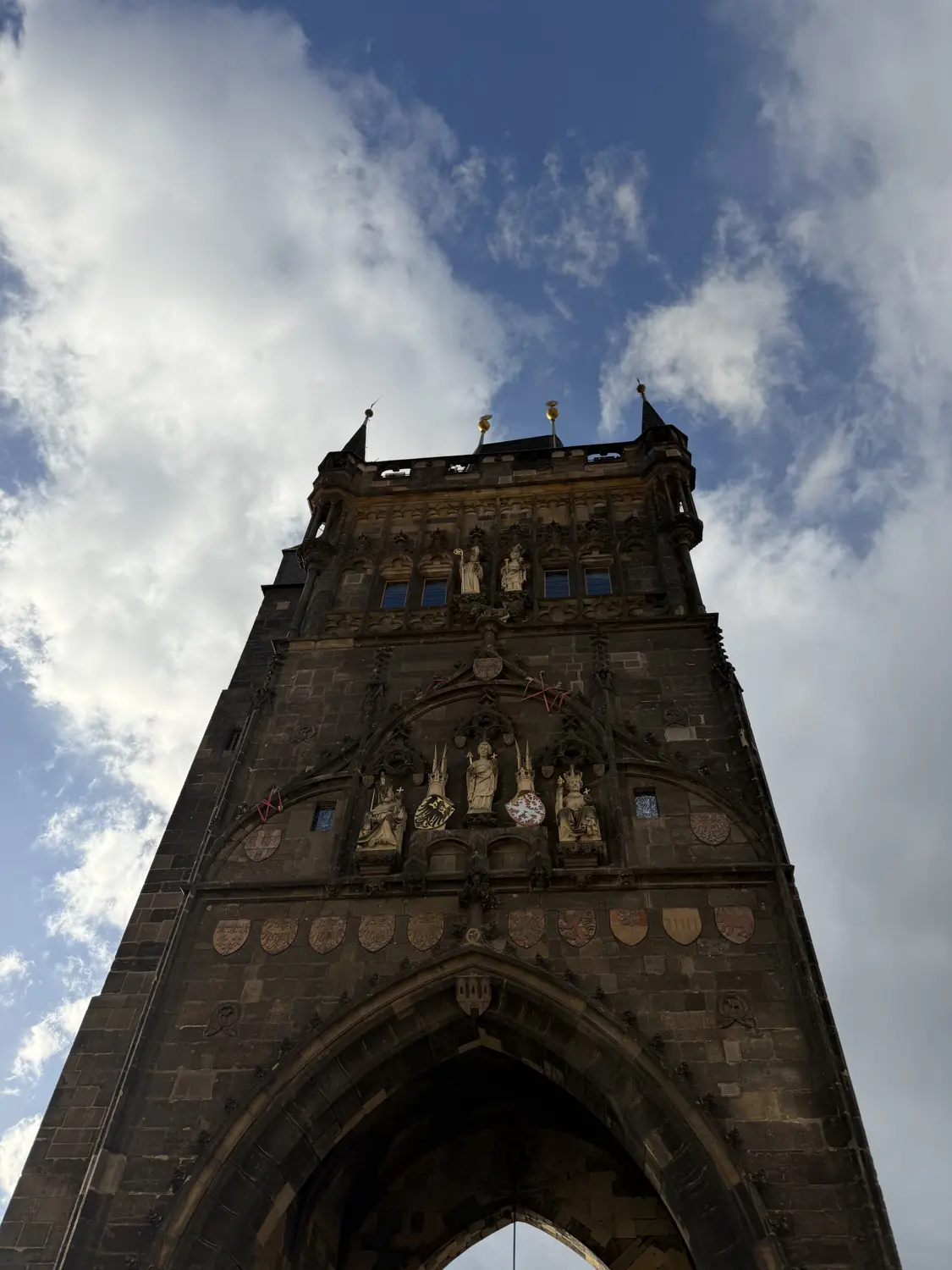 Looking up at the dark Gothic stone of a Charles Bridge tower