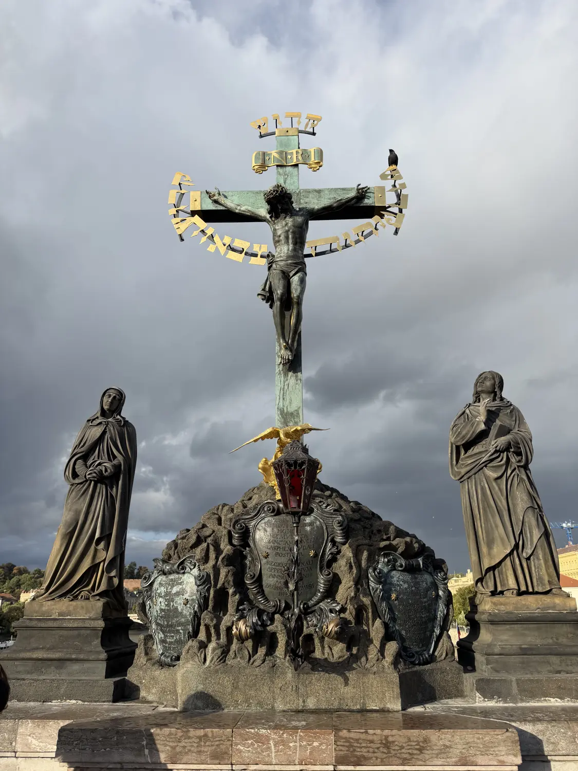 A dark bronze crucifix statue on Charles Bridge
