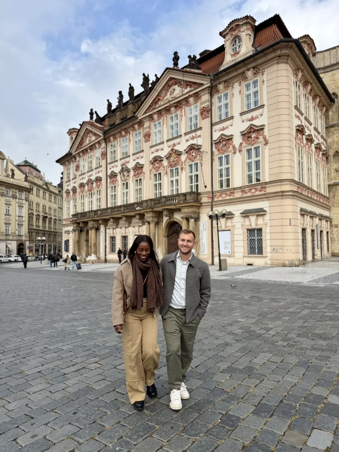 Us walking across Old Town Square in front of a pink baroque palace