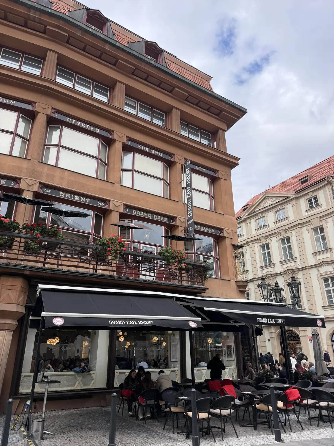 An old-town café with outdoor tables under a red-brick building