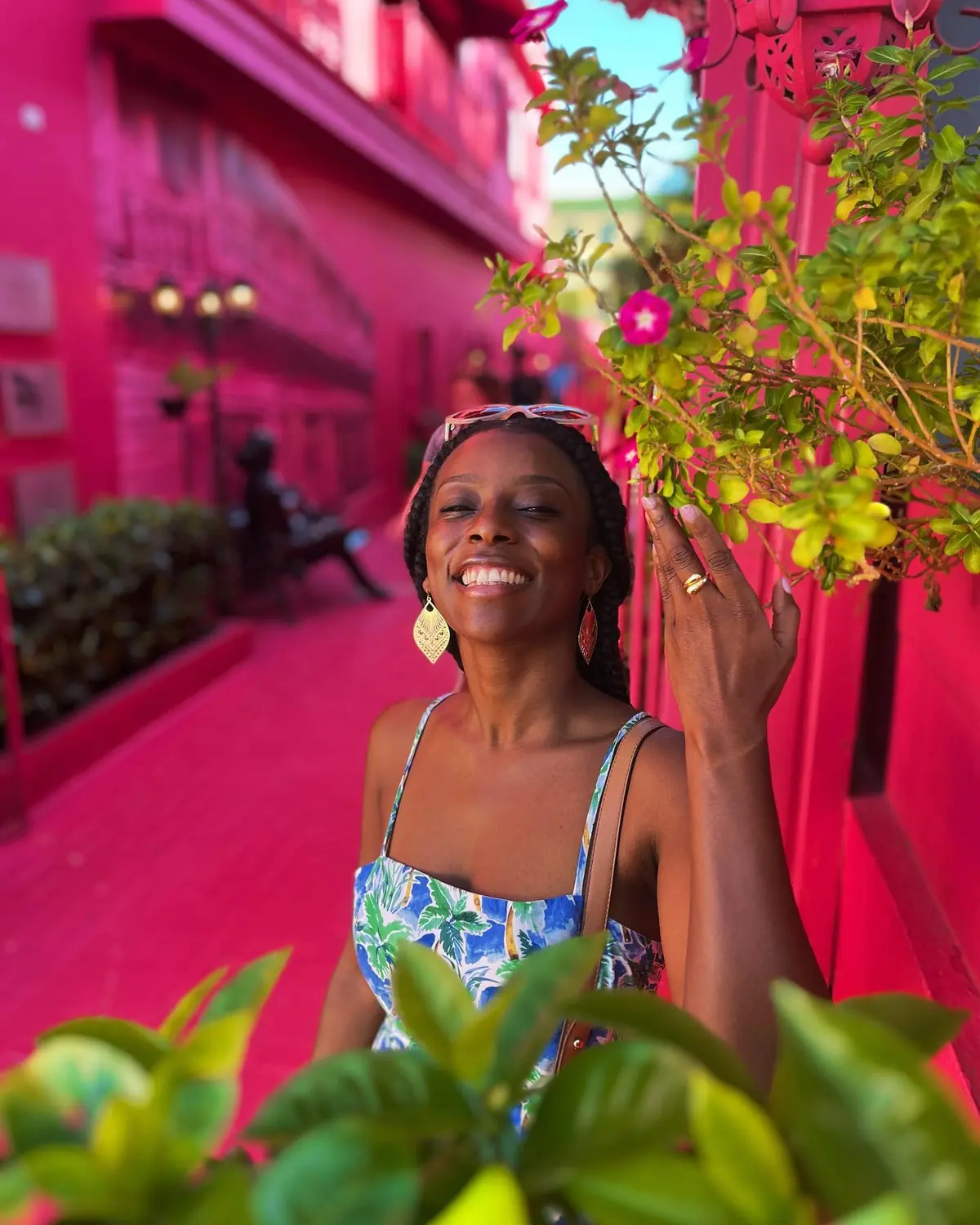 Melody smiling on Calle de la Doña Blanca, a bright pink street in Puerto Plata