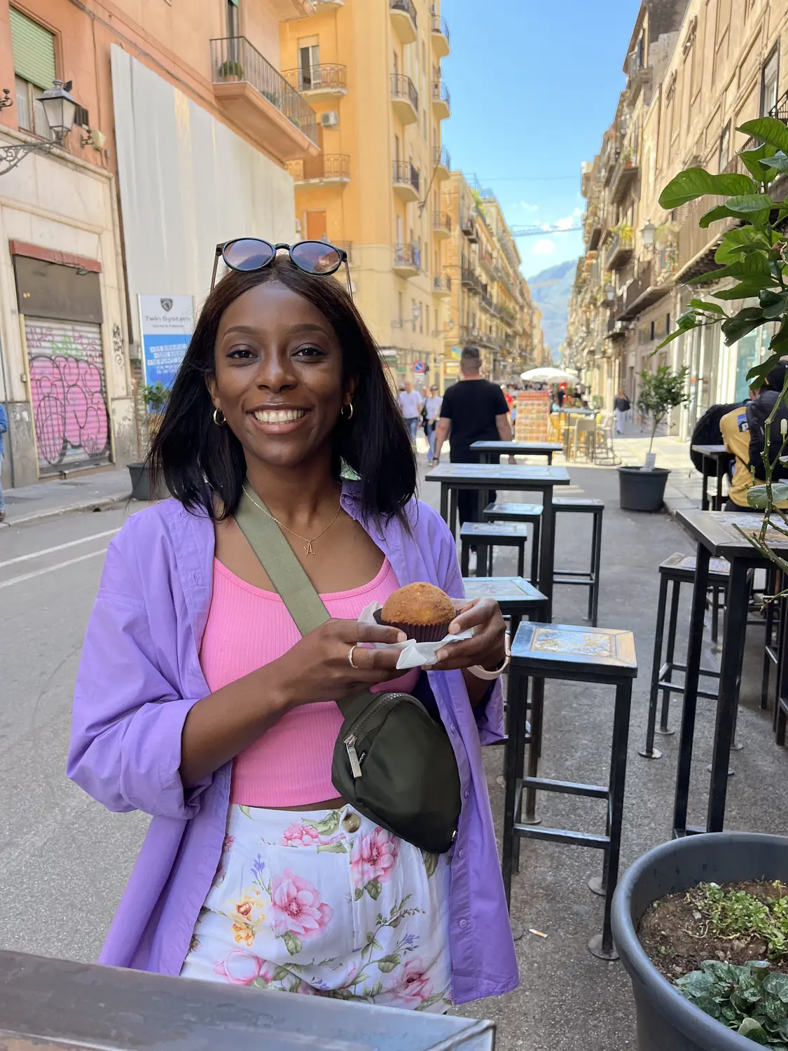 Melody holding a golden Sicilian arancino at a Palermo cafe