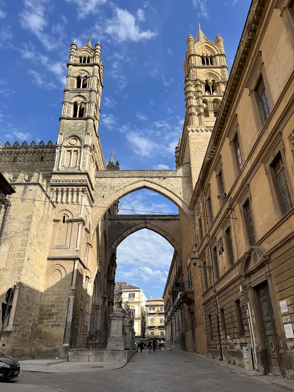 The pointed stone arch linking the towers of Palermo Cathedral over a quiet street