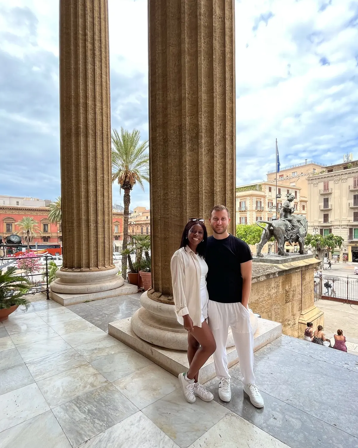 Us between the grand columns of the Teatro Politeama with a bronze statue behind, Palermo
