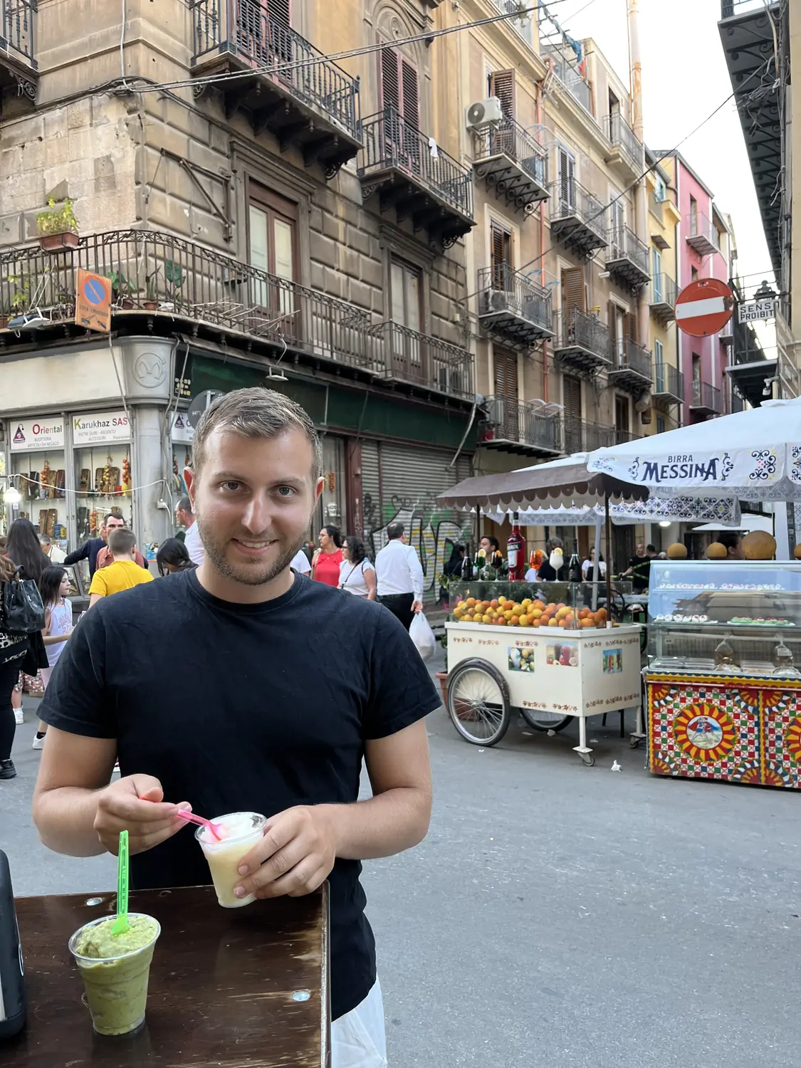 Andrew holding a frothy green lemon foam juice at a Palermo street food market