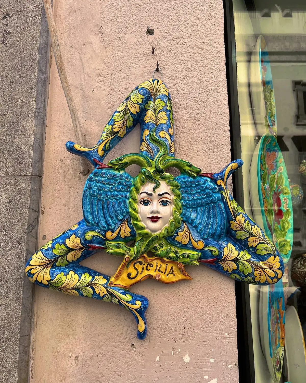 A hand-painted Sicilian Trinacria ceramic reading Sicilia on a Palermo wall