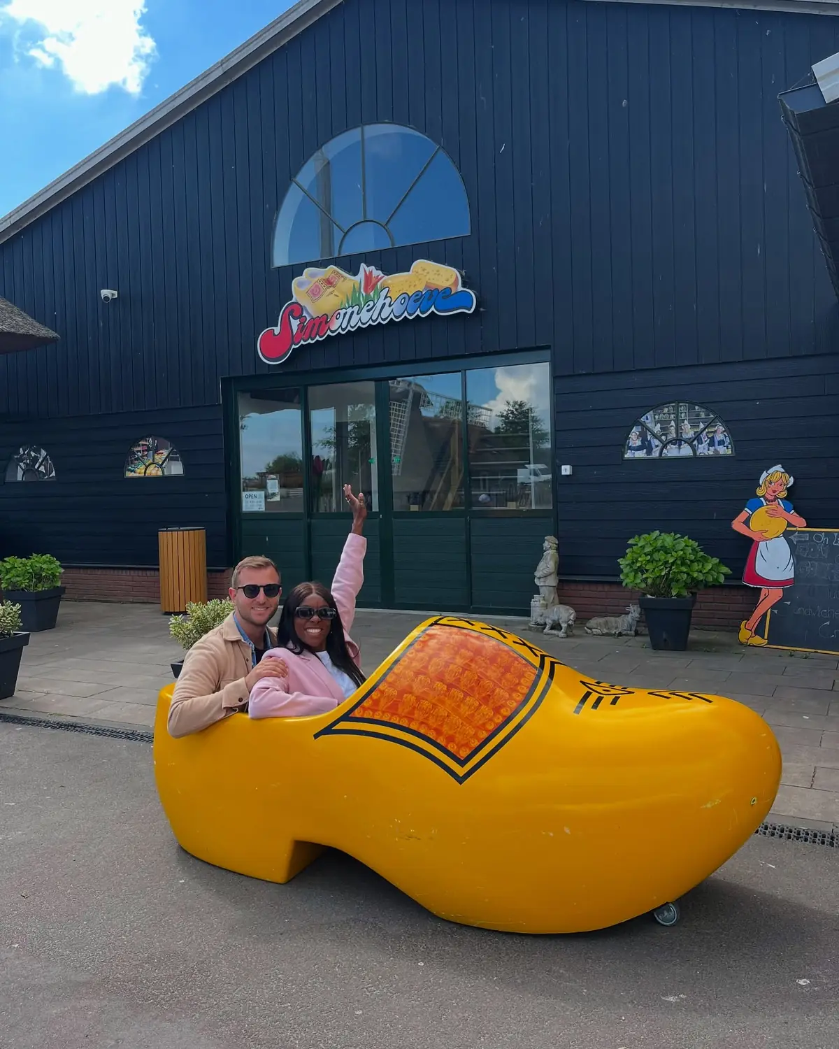 Us sitting inside a giant yellow wooden clog at the Simonehoeve cheese and clog farm