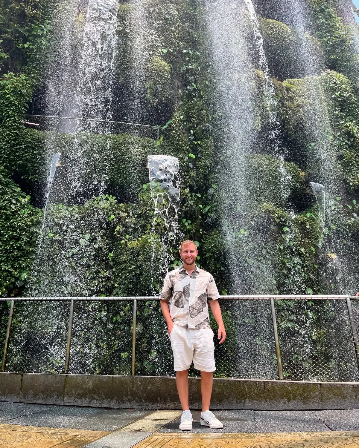 Andrew in front of the tall indoor waterfall inside the Cloud Forest dome