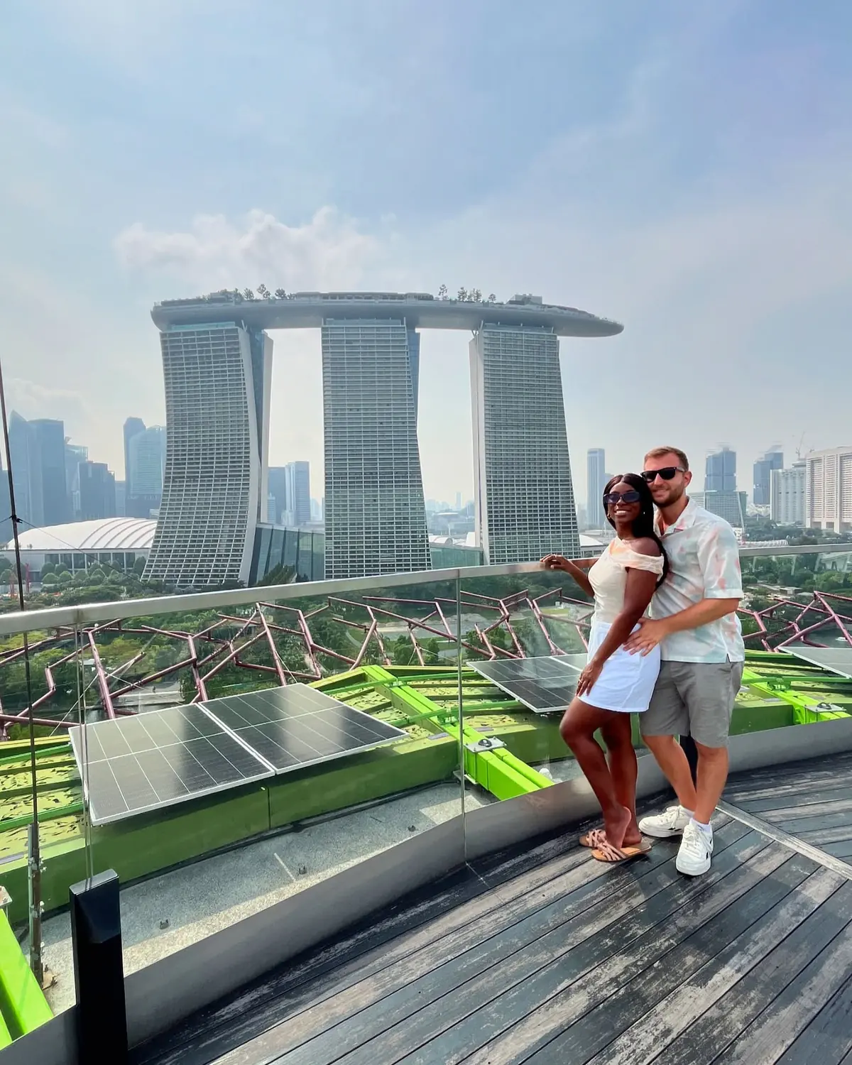 Us at a rooftop railing with Marina Bay Sands and the city skyline behind