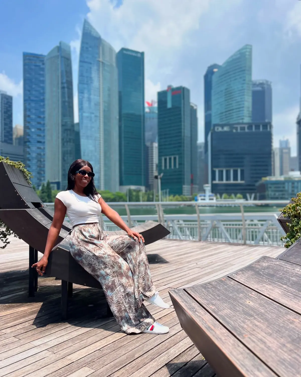 Melody sitting on a wooden lounger with the CBD skyline of Singapore behind