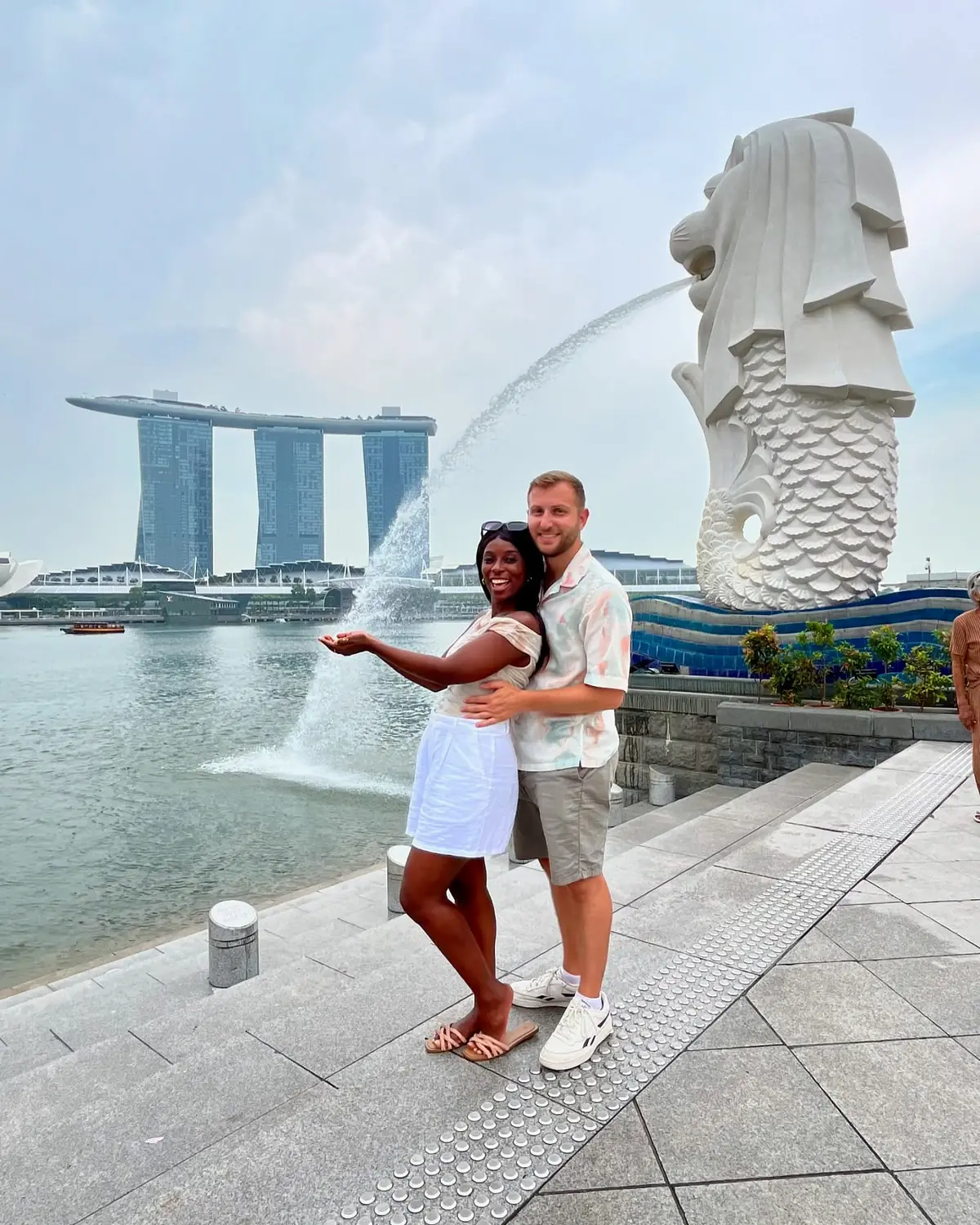 Us in front of the Merlion statue spouting water with Marina Bay Sands across the bay